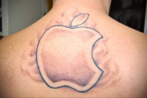 Фото татуировки на спине: минималистичное изображение логотипа Apple, выполненное в виде контура с легкой заливкой.