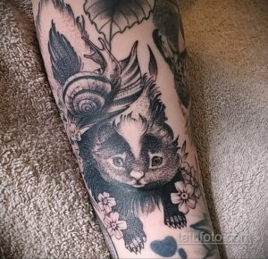 Фото тату енота с улиткой на спине, выполненное в технике dotwork с использованием черного и серого цветов. Детализированный рисунок татуировки.