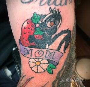 Фото тату лошади в стиле традиционной татуировки с клубникой и надписью 'MOM' на руке. Яркий и красочный рисунок татуировки.