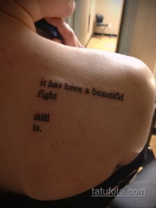 Фото тату: минималистичная надпись "it has been a beautiful fight still is." на плече, выполненная простым шрифтом.