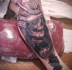 Фото тату самурая в доспехах, выполненного в стиле blackwork на руке. Детализированный рисунок с использованием точек и линий.