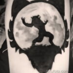 Фото силуэтной татуировки волка на фоне луны. Черно-белый рисунок татуировки с изображением волка, воющего на луну. Минималистичный и стильный дизайн.