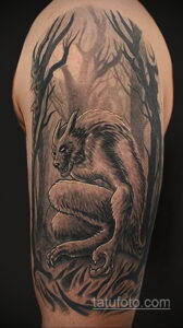 Фото тату оборотня, крадущегося в лесу, на руке. Детализированный рисунок в черно-серых тонах.