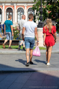Фото мужчины и девушки, идущих по улице. На руке мужчины видна татуировка с изображением головы животного.