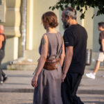 Фотография пары, идущей по улице. На женщине длинное платье, скрывающее возможные татуировки. Мужчина в черной футболке и брюках.