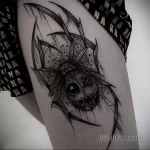 Фото татуировки паука с головой клоуна на ноге. Черно-белый рисунок в стиле dark art с множеством деталей и теней.