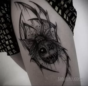 Фото татуировки паука с головой клоуна на ноге. Черно-белый рисунок в стиле dark art с множеством деталей и теней.