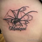 Фото тату паука на плече с надписью 'Monique'. Черно-белый рисунок паутины и паука, выполненный в реалистичном стиле.