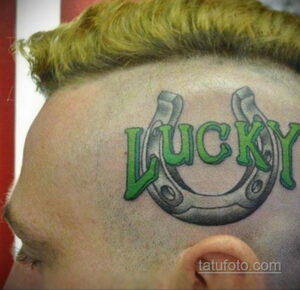 Фото тату надписи "Lucky" с подковой на лбу. Оригинальный рисунок татуировки в ярком стиле.