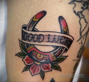 Фото тату подковы с надписью "Good Luck". Цветная татуировка в стиле олд скул с использованием красного, черного и зеленого цветов.