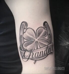Фото тату подковы с клевером и надписью "Granda". Детализированный рисунок татуировки в черно-сером стиле.