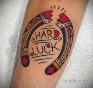 Фото тату подковы с надписью "HARD LUCK" в стиле традиционной татуировки. Простой, но эффектный рисунок татуировки с использованием черного цвета.