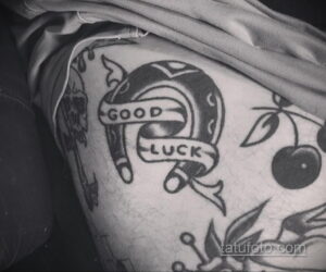 Фото тату подковы с надписью 'GOOD LUCK' в черно-белом стиле на руке. Рисунок татуировки с детальной проработкой контуров и теней.