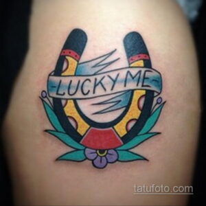 Фото тату на плече: две подковы с надписью 'LUCKY ME', выполненная в стиле олдскул с яркими цветами.