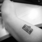Фото тату минималистичного контурного рисунка фотоаппарата на запястье. Простой и стильный эскиз татуировки.