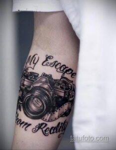 Фотография татуировки фотоаппарата с надписью "My Escape from Reality" на предплечье. Черно-белый рисунок с высокой детализацией.