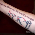 Цветная татуировка на руке с изображением кинопленки и надписи 'Let me show you the world in my eyes'. Романтичный и креативный дизайн.