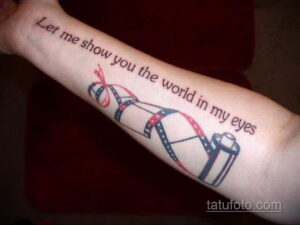 Цветная татуировка на руке с изображением кинопленки и надписи 'Let me show you the world in my eyes'. Романтичный и креативный дизайн.
