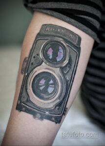 Фото тату: реалистичная черно-серая татуировка старинного фотоаппарата Rolleicord на икре. Детализированный рисунок, тени, реалистичная текстура.