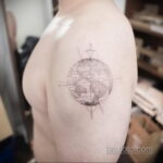 Фото тату: детальная карта мира, выполненная в технике тонких линий, расположена на плече. Реалистичный рисунок с акцентом на континенты и океаны.