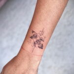 Фото татуировки на запястье с изображением ракеты. Техника dotwork, минимализм, тонкие линии, космическая тематика.