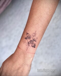 Фото татуировки на запястье с изображением ракеты. Техника dotwork, минимализм, тонкие линии, космическая тематика.