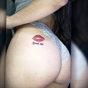 Фото тату с надписью "Spank Me!" и изображением красных губ на бедрах. Татуировка выполнена в минималистичном стиле и имеет провокационный характер.