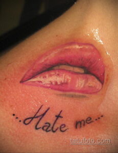 Фото тату на плече: глянцевые розовые губы и надпись 'Hate me'. Смелый и вызывающий рисунок татуировки для девушек.