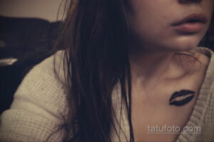 Фото тату: черные губы на ключице девушки. Минималистичный и загадочный дизайн татуировки, выполненный в темных тонах.