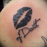 Фото тату на плече: отпечаток губ с надписью 'of Death' черным цветом. Минималистичный стиль, дерзкий дизайн, эскиз татуировки для девушек.