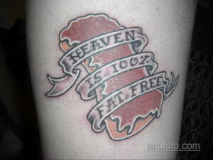 Фото тату: изображение шоколадной плитки с надписью 'HEAVEN IS 100% FAT FREE' в лентах. Черно-белая татуировка на руке.