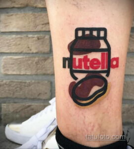 Фото тату с изображением банки Nutella на ноге. Яркий рисунок с четкими контурами и насыщенными цветами, выполненный в стиле минимализм.