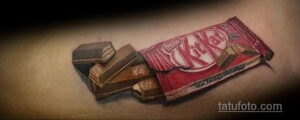 Фото тату шоколадного батончика KitKat с отломанными кусочками. Расположена на руке, реалистичный рисунок татуировки.