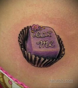 Фото тату конфеты в обертке с надписью "Eat me". Расположена на животе, яркий и красочный рисунок татуировки.
