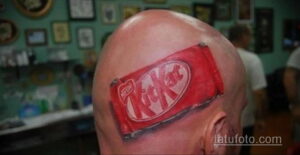 Фотография татуировки плитки шоколада KitKat, расположенной на лысой голове. Оригинальный и юмористический рисунок татуировки.