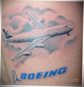 Фото реалистичной татуировки самолета Boeing на плече, выполненной в ярких цветах с использованием теней и бликов. Детализированный рисунок.