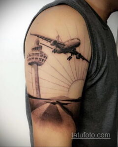 Фото тату на плече: реалистичное изображение самолета, взлетающего над аэропортом. Детализированный и впечатляющий рисунок татуировки.