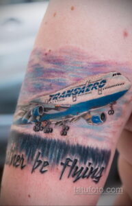 Фото тату: Детализированная реалистичная татуировка самолета Boeing 737 с надписью 'Never be Flying' на фоне облаков.