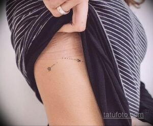 Фото минималистичной татуировки стрелы, выполненной тонкими линиями на боку. Изящный и лаконичный рисунок.