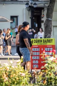 Фото тату на руке мужчины, идущего по улице с женщиной. Татуировка выполнена в темных тонах и покрывает большую часть предплечья.
