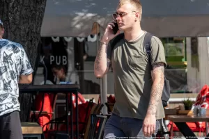 Фото мужчины в очках с видимыми татуировками на руках, демонстрирующими японские иероглифы и цветочные мотивы.