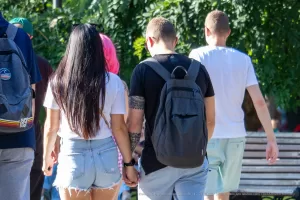 Фото тату: рука мужчины с татуировкой на предплечье, изображающей абстрактный узор, на фоне зеленой листвы.