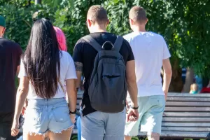 Фото тату: рука мужчины с татуировкой на предплечье, изображающей абстрактный узор, на фоне зеленой листвы.
