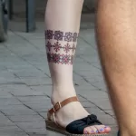 Красный славянский народный узор в цветной тату внизу ноги у девушки — уличная тату (street tattoo) № 15– tatufoto.com 230821 2