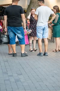 Фото тату на ноге мужчины: небольшой рисунок, расположенный на икре. Мужчина стоит в окружении людей на городской улице.