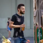Фото тату: татуировка на руке мужчины с изображением розы, обвивающей старинные часы. Рисунок выполнен в черно-серых тонах с высокой детализацией.