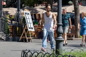Фото тату: мужчина с татуировкой в виде рукава на левой руке. Рисунок включает в себя портреты, геометрические узоры и абстрактные элементы.