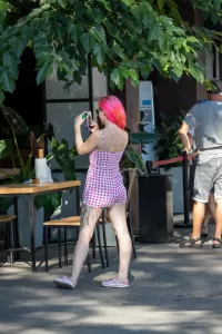 Фотография девушки с татуировкой дракона на спине, делающей фото на телефон. Вид сбоку, демонстрирующий детали татуировки.