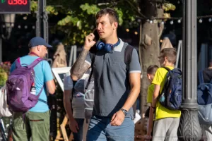 Фотография мужчины с татуировкой на руке, идущего по улице и разговаривающего по телефону. Татуировка выполнена в темных тонах и имеет сложный узор.