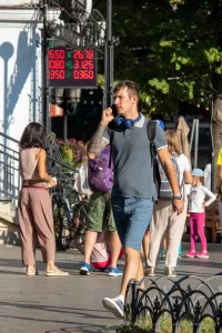 Фотография мужчины с татуировкой на руке, разговаривающего по телефону на улице. Татуировка выполнена в темных тонах и имеет сложный узор.